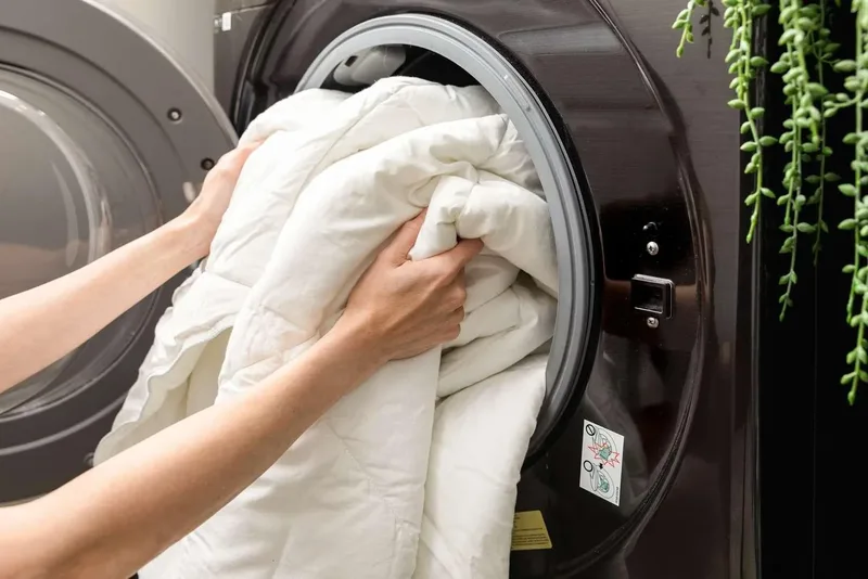 White bedding being loaded into a large commercial washer